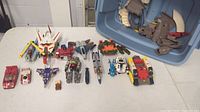 Overview of lot on table showing multiple vintage Transformers figures, vehicles, and parts.