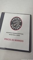 Front cover of the binder showing a printed sheet with Toronto Raptors logo and text "Assorted Toronto Raptors Basketball Cards PRICES AS MARKED."