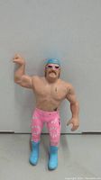Front view of 1986 Jesse 'The Body' Ventura wrestling action figure showing muscular torso, pink floral wrestling pants, blue boots, blue bandana and sunglasses.
