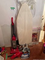 Full view of the vacuum cleaner, ironing board, and two irons on floor