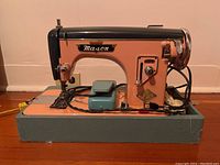 Front and side views of the Mason De Luxe vintage sewing machine sitting on a blue-green base, showing peach and black color scheme, metal parts, foot pedal and attached cords.