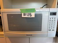 Front view of white Panasonic microwave oven with closed door and keypad on right side.