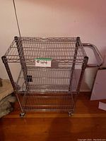 Full front view of the rolling metal wire shelf cart showing 3 shelves and wheels.