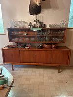 Front view of two-piece teak china cabinet showing glass-front upper display and lower sideboard with four sliding doors.