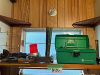 Shelf with green metal toolbox and extra tools including hammer and other items.