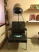 Full front view of the salon chair with attached dome hair dryer and patterned upholstery, positioned against a wall with framed pictures.