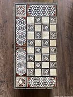 Closed view of checkers side with intricate inlaid geometric pattern in mother-of-pearl and wood mosaic