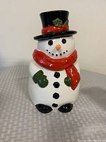 Front view of the ceramic snowman cookie jar showing detailed colors and decorations including hat, scarf, buttons, mittens, eyes, mouth, and nose.