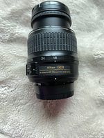 Close-up image of a Nikon AF-S DX NIKKOR 18-55mm f/3.5-5.6G ED lens showing details of zoom markings, focus ring, and autofocus switch.