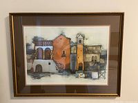 Full view of framed art showing stylized buildings in warm tones.