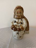 Front view of the ceramic snowman tea light candle holder with scarf and mittens, star cutouts in body