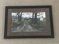 Framed print showing a rural dirt road scene, trees, and houses with 'The Road Home' signature on the bottom right.