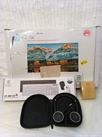 Photo showing the HP 27FW monitor box, wireless keyboard and mouse combo box, Aukey webcam box, and Jabra headset case.