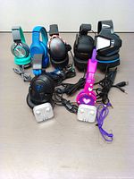 Photo of 7 over-ear wired headphones and 2 pairs of wired earbuds in plastic cases, shown on a wooden surface.