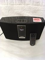 Front-facing view of black Bose SoundTouch 20 speaker with fabric grille and silver display panel, remote positioned at right