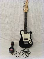 Photo of Donner electric guitar and Sony MDR-V6 headphones side by side on beige fabric background.