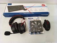 Overall photo of all items included in the lot showing the headset, CPU fan, Redragon gaming mouse, and Insignia keyboard box.
