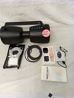 Bundle of Monster portable speaker, smartwatch, and cables arranged on white surface.