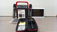 All items from the multimedia bundle arranged showing two wireless microphones, the karaoke machine, tablet, and microphone case with accessories.
