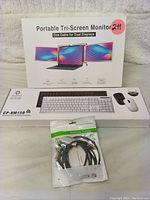 Box packaging showing Portable Tri-Screen Monitor, wireless keyboard and mouse combo, and deluxe cables laid out.