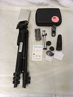 Overview of the lens kit items and power bank showing the two tripods, phone holder, lens clip, cleaning cloths, instruction manual, and power bank.