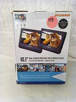 Box packaging of Sylvania 10.1" Dual Screen Portable DVD Headrest System showing branding and features, indicating dual 10.1" high resolution LCD screens.