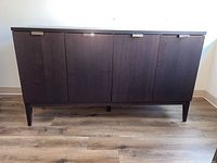 Front view of dark wood cabinet showing four doors and metal handles.