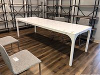 Side view of white rectangular table with metal legs and glossy finish