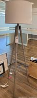 Full view of a tripod floor lamp with light fabric shade in an office setting.