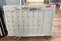 Full view of glass calendar white board showing monthly grid and date squares with handwritten month and notes section.