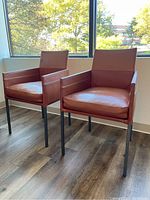 Front view of two brown leather armchairs positioned side by side before a window