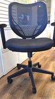 Front view of black office chair with mesh backrest and cushioned seat, showing adjustable armrests and wheeled base.