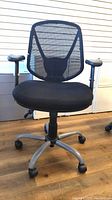 Front view of black mesh office chair with padded seat and armrests.