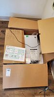 Opened cardboard box showing APC UPS unit in original packaging with installation guide