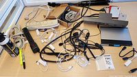 Overview of lot with power strips, cords, tripod, pen tablet, iPhone and accessories on a table