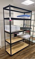 Front view of black metal shelving unit holding plastic trays and containers.