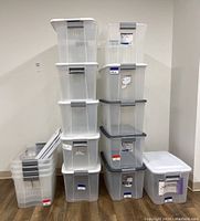 Two vertical stacks of Sterilite bins and lids against a white wall on wood flooring