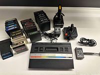 Full setup with Atari 2600 console, two joysticks, RF connection box, numerous game cartridges arranged in groups