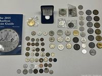Wide view of all coins arranged on table with Charlton Coin Guide book and 1992 Ontario commemorative coin in display case.