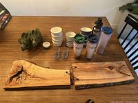 Two images showing a kitchen lot containing wooden serving boards, small ceramic bowls, glass containers, travel tumblers, and a plastic container on a wooden table.