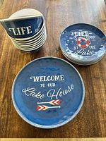 Photo showing stacked blue plastic bowls and two groups of plates with lake themed text and graphics