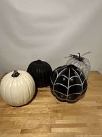 Four decorative pumpkins on wooden surface with varied finishes and designs.
