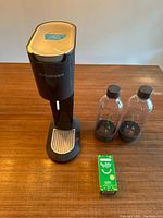 Full view of SodaStream machine in black, two clear bottles with black caps, and small green Bubly syrup box