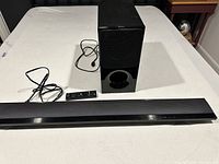 Overview of soundbar, subwoofer, remote and power cables on table