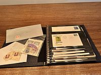 Photo showing open binder with stamps and several envelopes in plastic sleeves including some with Canadian postage and commemorative postmarks