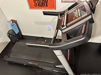 Side view of the treadmill showing the running belt, the frame, and the folded rollers on the side.