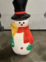 Front view of vintage plastic outdoor Frosty the Snowman light-up decoration showing details of the face, hat, scarf, and hands.