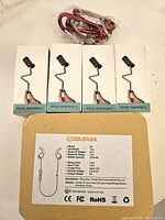 Four white boxes each containing a collapsible straw, with a bundle of black and red wired headphones on top. Box labels show collapsible straw text.