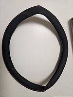 Full view of the black universal steering wheel cover with red stitching on white background showing the textured material and shape.