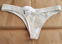 Front view of Calvin Klein ribbed thong, showing detailed rib knit fabric and elastic waistband with brand tag.